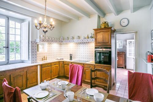 - une cuisine avec une table, des chaises et une cuisinière dans l'établissement La Cour d'Audouville, à Audouville-la-Hubert