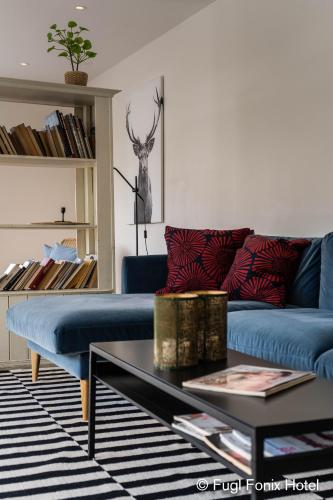 a living room with a blue couch and a table at Fugl Fønix Hotel in Etnesjøen