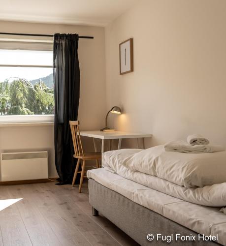 a bedroom with a bed and a desk and a window at Fugl Fønix Hotel in Etnesjøen