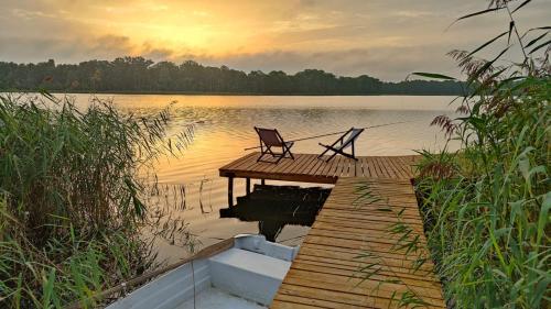 a dock with two chairs sitting on top of a lake at Siedlisko Pozorty in Pozorty