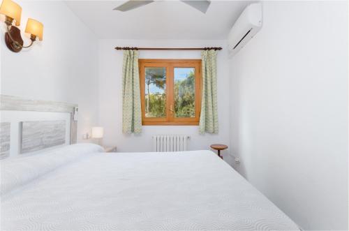 Un dormitorio blanco con una cama blanca y una ventana en YourHouse Binifat, en Andratx