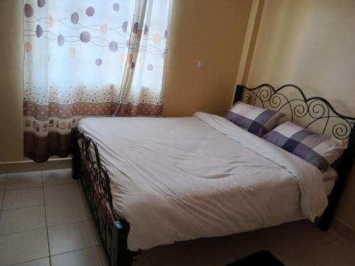 a bedroom with a bed and a window with a curtain at Rubi Apartment in Naivasha