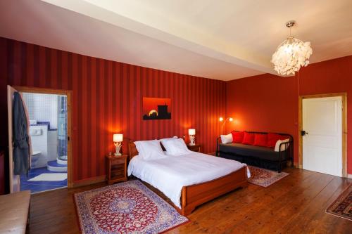 1 dormitorio con paredes rojas, 1 cama y 1 sofá en Domaine de Seugnac, en Pons