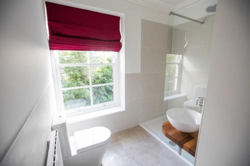 a bathroom with a white toilet and a window at Bishop's Gate Hotel in Derry Londonderry