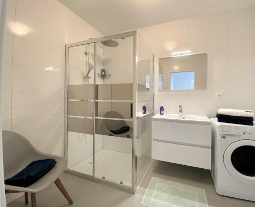 La salle de bains blanche est pourvue d'une douche et d'un lave-linge. dans l'établissement 