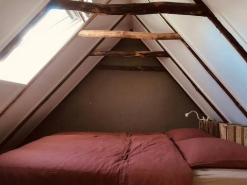 a bed in a room under a roof at Tiny House De Smederij in Peize