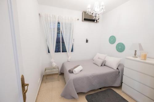 a white bedroom with a bed and a window at Agradable Villa con piscina in Seville