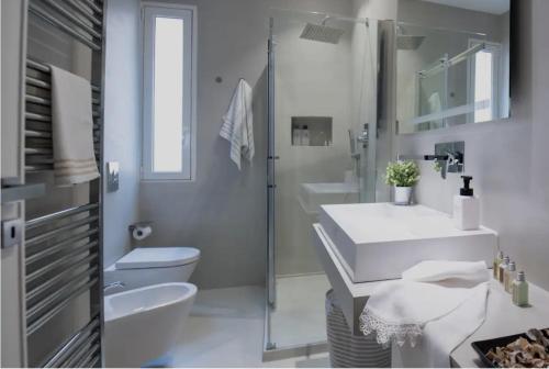 a white bathroom with a toilet and a sink at A due passi dal mare in Trapani