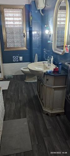 a bathroom with a sink and a toilet and blue walls at ToMa House in Pellaro