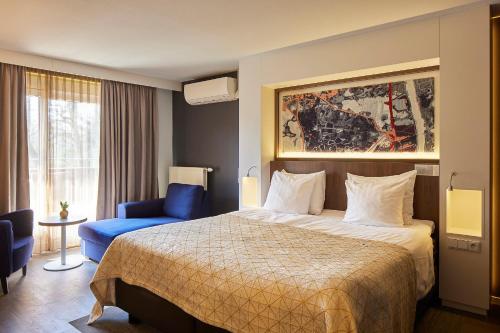 Pokój hotelowy z łóżkiem i niebieskim krzesłem w obiekcie Auberge Du Bonheur w mieście Tilburg