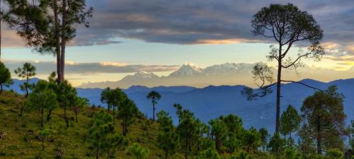 a view of a mountain range with trees in the foreground at Majkhali Woods, Ranikhet, By Himalayan Eco Lodges in Rānīkhet