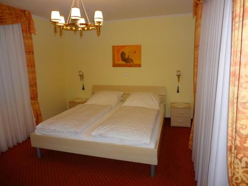 una camera da letto con un letto con lenzuola bianche e un lampadario a braccio di Ferienhaus Lohberg a Lohberg