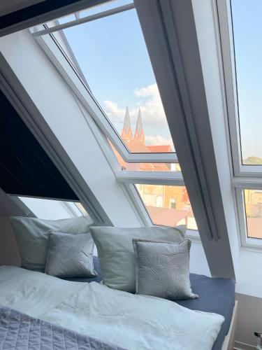 een bed met kussens in een kamer met ramen bij Ferienwohnung Kamrath mit wunderschönem Ausblick in Neuruppin