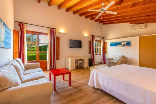 a bedroom with a bed and a couch and a tv at Finca Son Roig by Valentin in Porreres