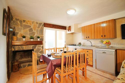 uma cozinha com uma mesa e uma cozinha com uma lareira em Casa Pepa em Igualeja