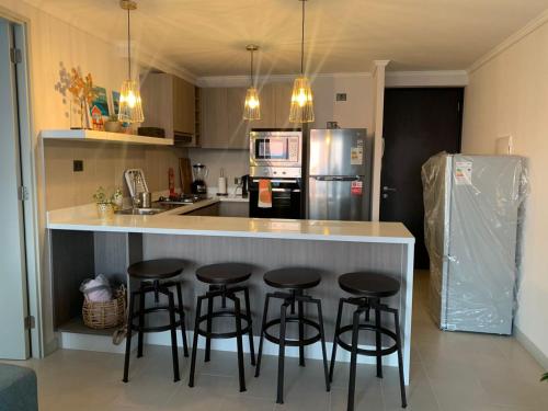 a kitchen with a counter with four bar stools at Departamento frente al mar en Arica in Arica