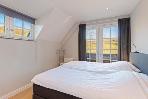 Schlafzimmer mit einem großen weißen Bett und Fenstern in der Unterkunft Residentie Heesdael in Slenaken