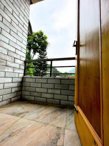 an open door to a balcony with a brick wall at The Wild Yak in Mandi