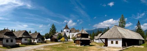 a group of buildings with a church in the background at Chalupa Liptovský Mikuláš in Liptovský Mikuláš