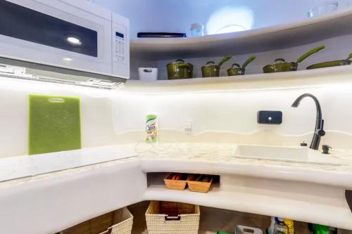 a kitchen with a sink and a microwave at Alterhome Swan villas with swimming pool and ocean views in Placencia Village