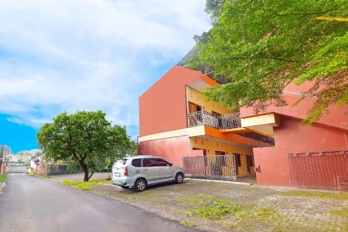 un coche aparcado frente a un edificio rosa en OYO 90463 A2b Guesthouse, en Manado