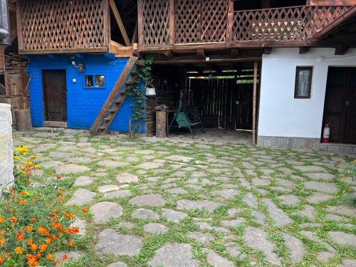 a house with a blue wall and a patio at Casa de vacanta traditionala romaneasca in Schiuleşti