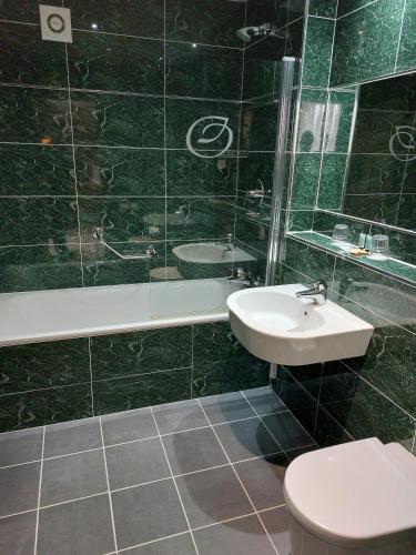 a bathroom with a sink and a toilet and a tub at Owston Hall Hotel in Doncaster