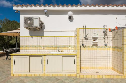 a house with a yellow and white kitchen with a fan at Villa Chiara in SantʼAntìoco