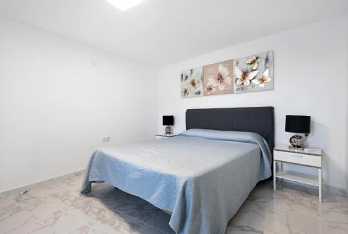 a white bedroom with a bed with a blue blanket at Casita Auxilia Bajo in Araya