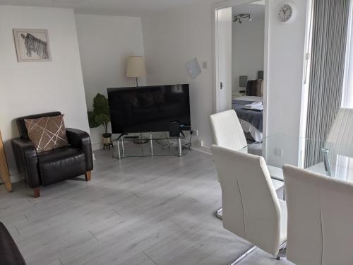 a living room with a television and a table and chairs at Glasgow City Centre Waterfront Apartment in Glasgow