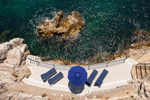 an aerial view of a beach with blue umbrellas and the ocean at Villa Levante - Direct Sea Access - Full Sea View - Amalfi Coast in Cetara