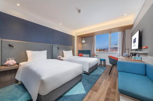 una camera d'albergo con due letti e un divano di Holiday Inn Express Shanghai Jiading Center, an IHG Hotel a Shanghai