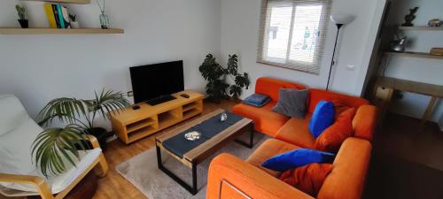 sala de estar con sofá naranja y TV en San Felipe Penthouse, en Puerto de la Cruz