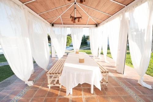 uma mesa e cadeiras sob uma marquise com cortinas brancas em Agradable Villa con piscina em Sevilha