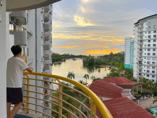 a man standing on a balcony looking out at a river at BayView Suites Port Dickson By MAISON in Port Dickson