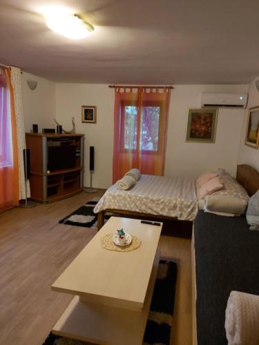 un soggiorno con 2 letti e un tavolo di Studio apartman KOTRO a Beli Manastir