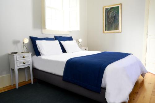 a bedroom with a blue and white bed and a window at Casa Galricho in Murtosa