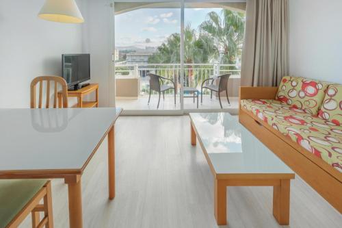 ein Wohnzimmer mit einem Sofa und einem Tisch sowie einem Balkon in der Unterkunft Club Simó in Cala Millor