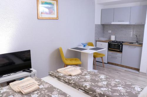 um pequeno quarto com uma cozinha e uma mesa com cadeiras em Zlatne perle em Vrdnik