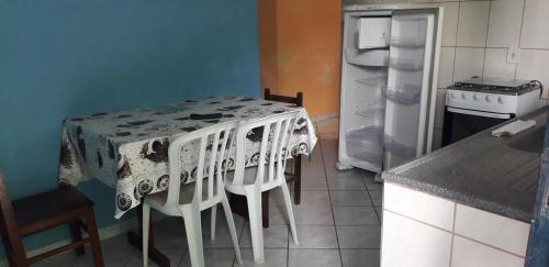 a kitchen with a table with chairs and a refrigerator at Centro Ilha comprida in Ilha Comprida