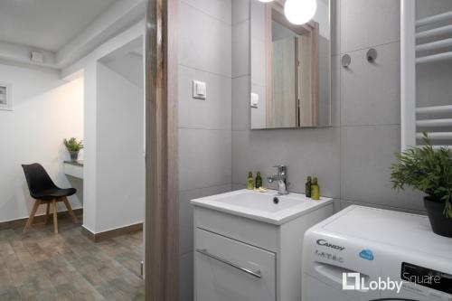 a white bathroom with a sink and a mirror at Embassy Studio by LobbySquare in Athens
