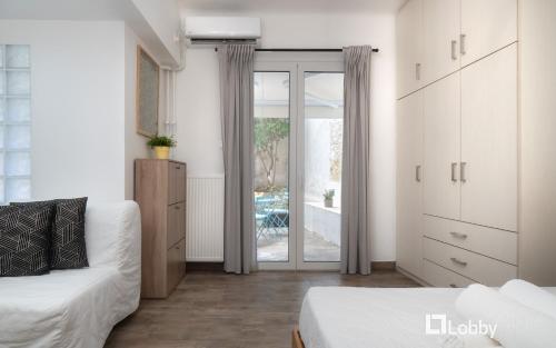 a white room with a bed and a sliding glass door at Embassy Studio by LobbySquare in Athens