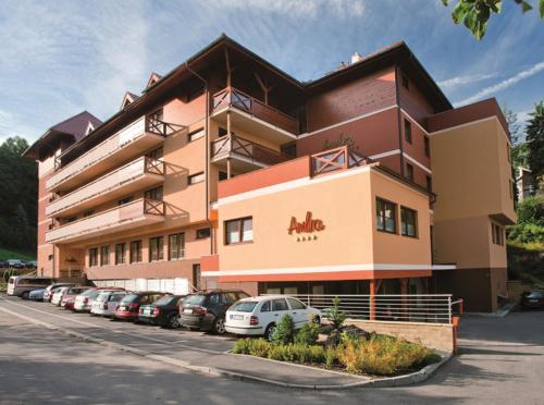 un edificio con coches estacionados en un estacionamiento en Hotel Ambra, en Luhačovice