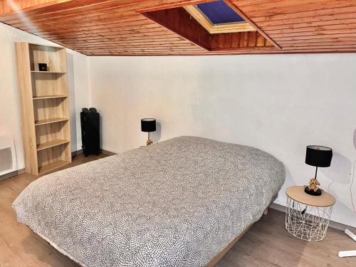 Villa 2 chambres proche d’un Lac في Ruelle-sur-Touvre: غرفة نوم بها سرير مع مصباحين