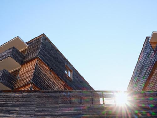 a building with the sun shining behind it at Hotel Planai by Alpeffect Hotels in Schladming