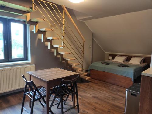 a room with a bed and a table and a staircase at Apartamenty Madzia in Wisła