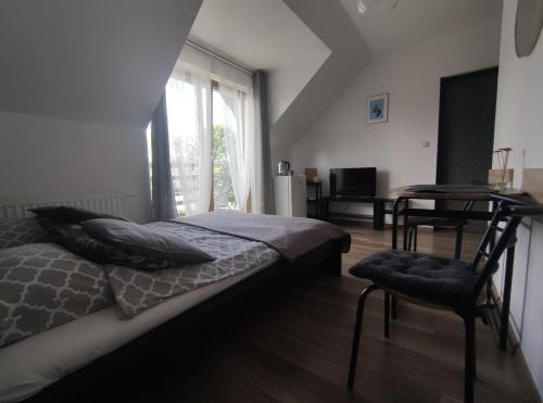 a bedroom with a bed and a desk and a window at Kwatery PogodneWczasy w Jantarze in Jantar