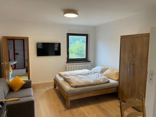 a bedroom with a bed and a couch and a tv at Ferienwohnung mit Wasserzugang in Lychen