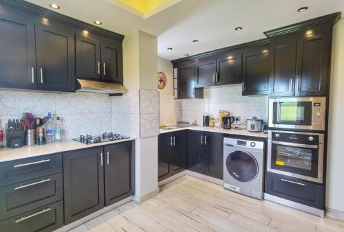 a kitchen with black cabinets and a washer and dryer at PERFECT APPART Grand Baie Centre Next To Super U, 5 Minutes from beach in Grand Baie