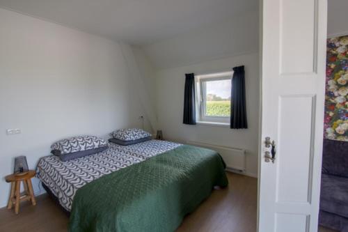 Schlafzimmer mit einem Bett und einem Fenster in der Unterkunft Oppe Klincke in Franeker